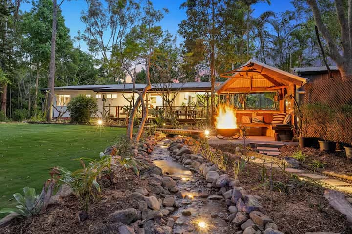 Completed display creek with rock stream, fire pit and garden lighting at dusk