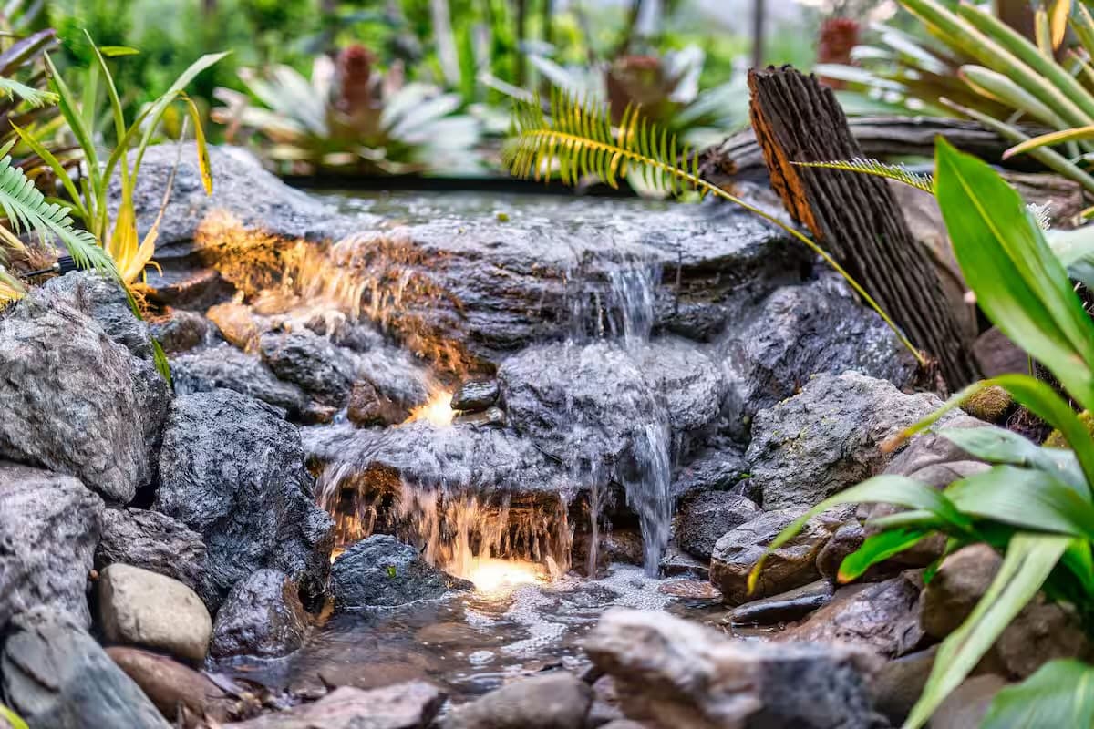 Rock waterfall feature with cascading water and fern planting